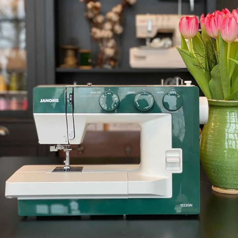 Grønn Janome symaskin på et bord med tulipaner i butikken til Kakle